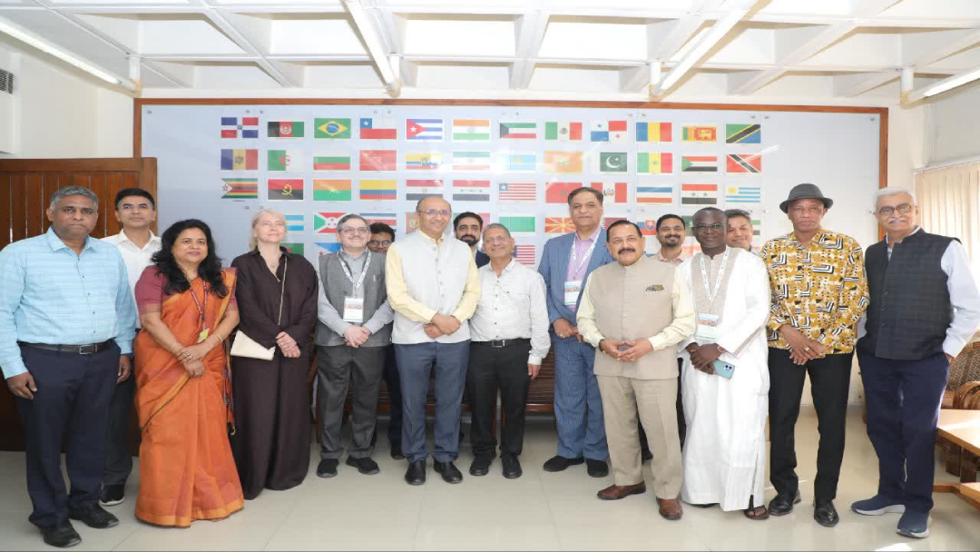 Group photo of diverse attendees at the 31st ICGEB Board of Governors Meeting, standing in front of a display of international flags, highlighting the global participation in the event.